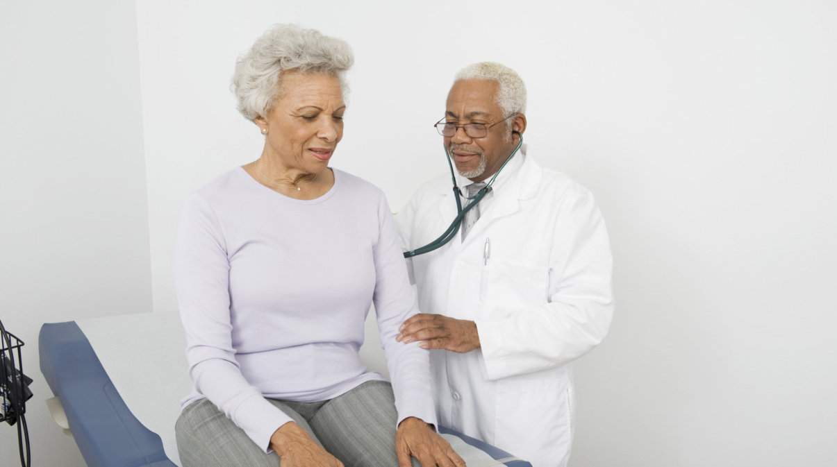 doctor checking senior woman's back with stethoscope