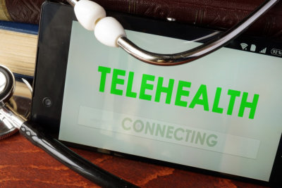Telehealth apps open in a smartphone and stethoscope.